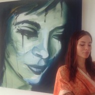 Actress standing in front of a painting of her on set of Blood Orange.